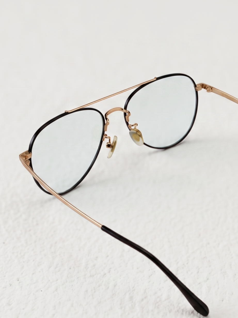 Close-up shot of double bridge fashion clear lens glasses metal hinge and nose pad, sleek two-tone aviator frame texture fashion eyewear detail photography plain white background