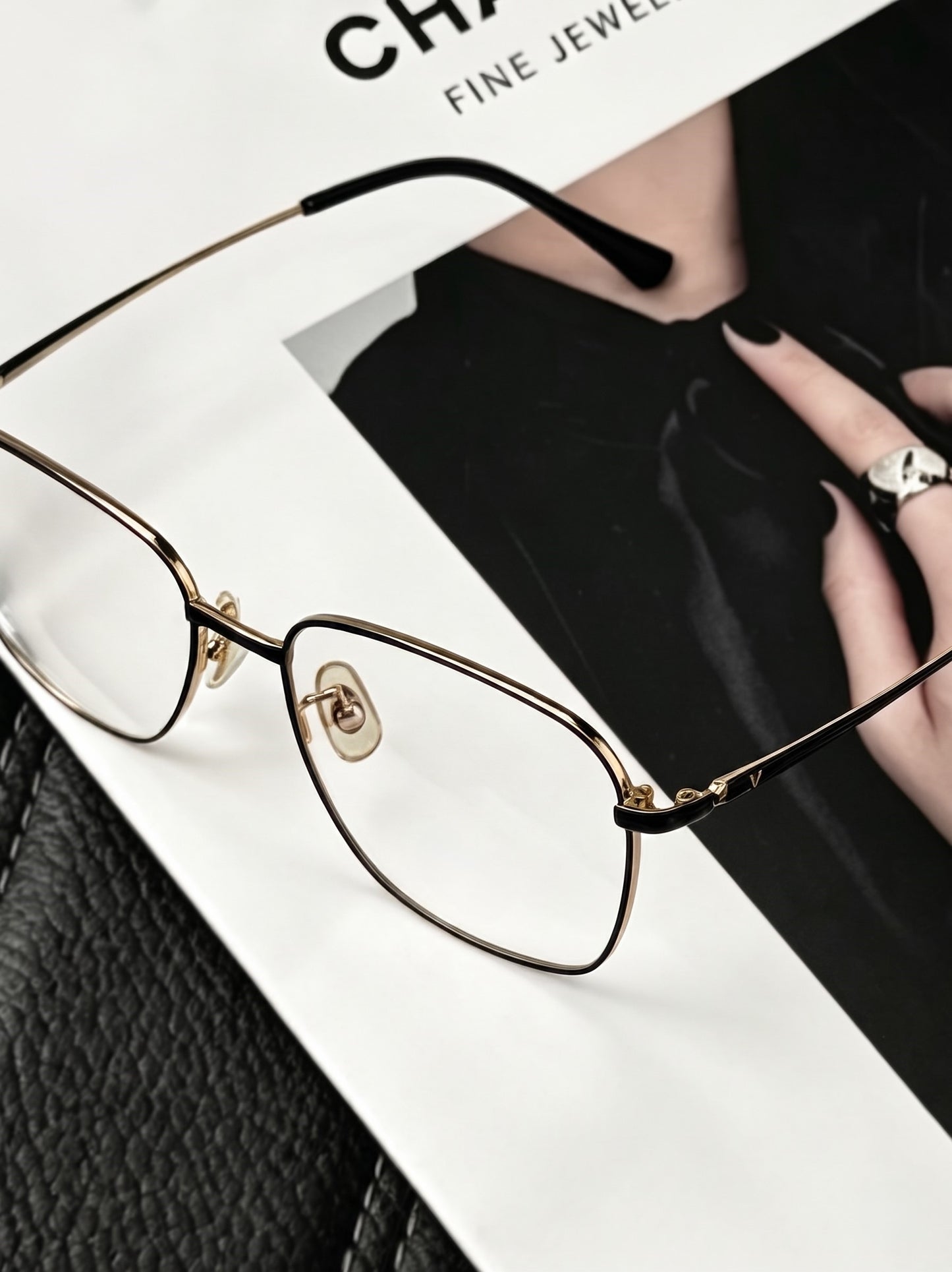 Close-up shot of gold black thin metal glasses frames on luxury fashion magazine, sleek thin metal square eyeglass frame hinge detail car interior product styling